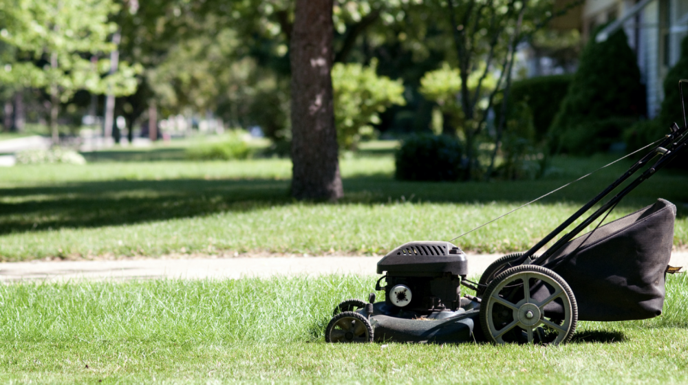 A black lawn mower mowing a yard.