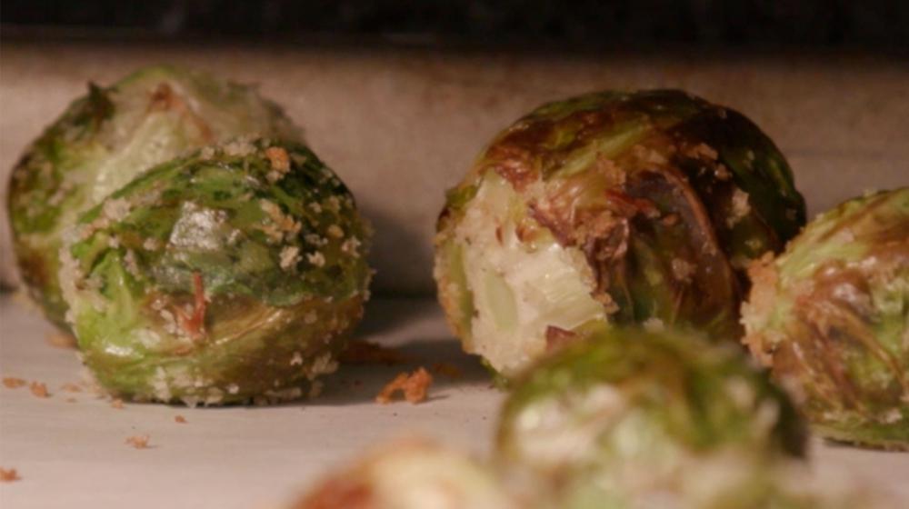Close-up of roasted Brussels sprouts coated with Panko breadcrumbs on a sheet pan covered with parchment paper.