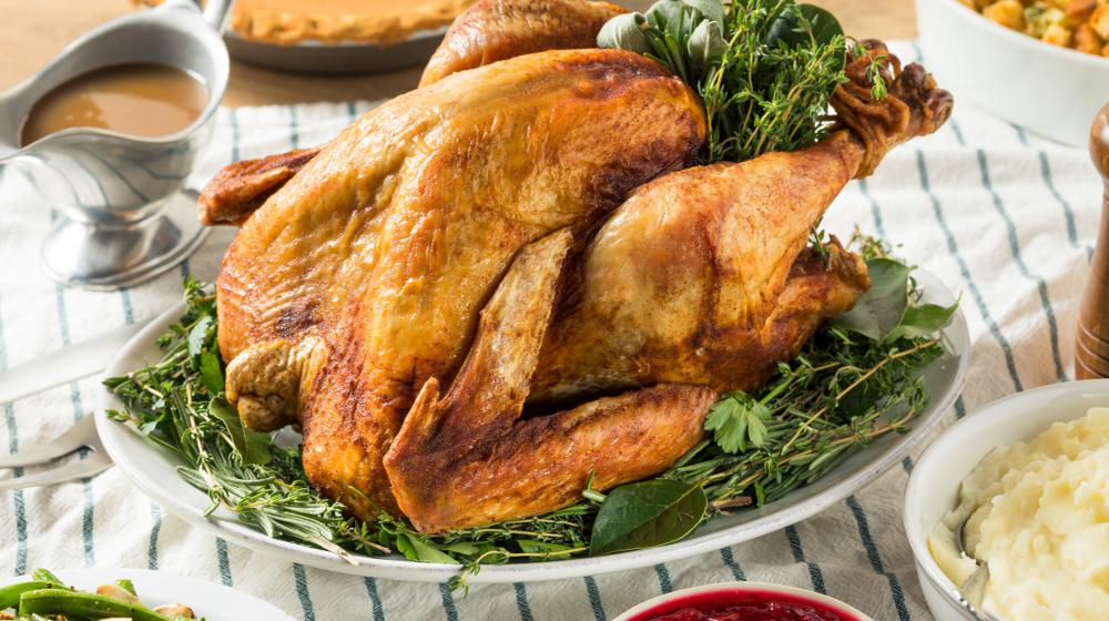A roasted turkey surrounded by traditional side dishes.