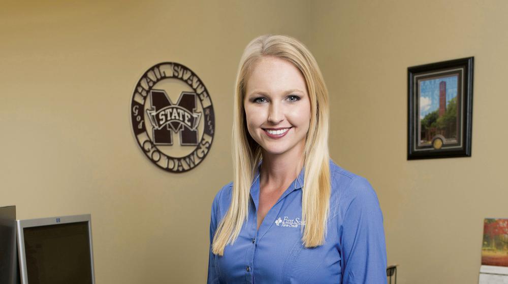 A smiling woman in a blue shirt poses for the camera.