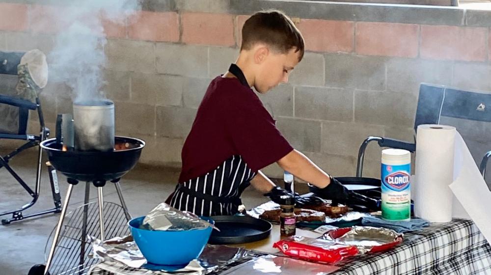 Young 4-H student grilling, preparing food