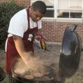 Mississippi State University Collegiate 4-H member Billy Hudson, 19, of Greenwood tries his hand at grilling during one of the club's recent football tailgates. While club members often get together to socialize, they make community service a priority. (Photo by Patti Drapala)
