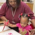 Avis Taylor, a field technical assistant with the Mississippi Child Care Resource and Referral Network, makes handprint butterflies with Eden White, 1, at West Kemper Kiddie Kollege in De Kalb.