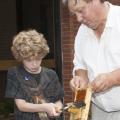 MSU Extension entomologist Jeff Harris holds a bee frame while Emmett King, 10, carefully harvests the honey. Beekeeping was one topic covered in Mississippi State University's 20th annual Bug and Plant Camp. (Photo by MSU Ag Communications/Kat Lawrence)