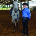 White horse stands beside teen boy with blue dress shirt and black cowboy hat