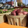 Red potatoes in a biodegradable basket are flanked on either side by green snap beans.