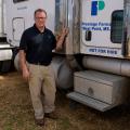 A man stands next to an 18-wheeler truck.