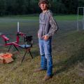 A boy standing beside a sport shooting range smiling.