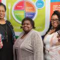 Three women standing in front of a MyPlate banner.