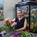 A young woman smiling while arranging a bouquet of flowers.