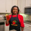 A woman holds a glass of strawberry gree tea in a kitchen.