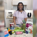 A woman stands in front of a kitchen counter filled with food products.