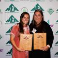 Two women stand while holding award plaques at the Mississippi Forestry Association annual meeting. 