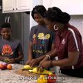 A woman and two children slice vegetables