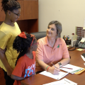 Woman filling out paper work with two children. 