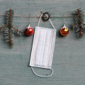 A white mask hanging on Christmas garland.