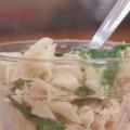 Cooked chicken, noodles, and spinach in a clear glass bowl