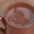 Hot cocoa sprinkled with cinnamon in a terra cotta mug