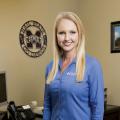 A smiling woman in a blue shirt poses for the camera.