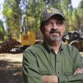 A man stands near a logging operation.