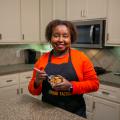 A woman stands in a kitchen and holds a bowl of Cinnamon Fried Pineapple