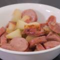 A bowl of cooked sausage and apples.