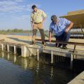 Split-cell catfish ponds circulate oxygen-rich water from the larger lagoon through channels to the smaller side where catfish grow. On March 21, 2017, Mississippi State University Extension aquaculture specialist Mark Peterman, left, and Jeff Lee of Lee’s Catfish in Macon examined the fencing that contains fish in this Noxubee County catfish pond. (Photo by MSU Extension Service/Kevin Hudson)