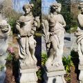 Four stone statues are seen representing ancient Greek goddesses.