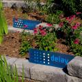 Blue signs stating “absorb” and “delay” mark brick tiers in a landscape growing pink flowers and reed-like stems.