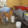 Man leans over a 5-gallon bucket placed under a large mechanical unit inside a building.