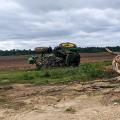 Green tractor flipped on its side in a field.