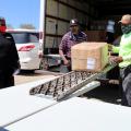 Three volunteers unload boxes from an 18-wheeler.
