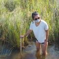 Girl wading knee-deep in water measuring its depth with a yardstick