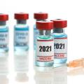 Two medical ampoules of COVID-19 vaccine with a syringe.