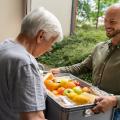 A man delivers a food box to a senior citizen.
