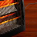 Close up of an electric space heater sitting on a hardwood floor.