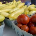 Close up of tomatoes and yellow squash in farmers market baskets.