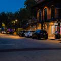 A night view of a downtown street in Ocean Springs, Mississippi, lined with shops and parked cars.
