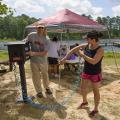 Jim McAdory, Mississippi State University Extension Service agent to the Mississippi Band of Choctaw Indians, shows Natasha Willis how to use the sunscreen dispenser provided by MSU Extension. The demonstration was part of a May 28 boating event in Neshoba County, Mississippi. (Photo by MSU Extension Service/Kevin Hudson)