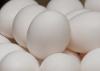 A close up of white eggs stacked in a bowl with other white eggs.