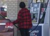 An adult pumps gas into a car at a gas station.