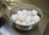 White eggs fill a metal bowl on a countertop.