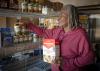 A woman puts nonperishable food on pantry shelves.