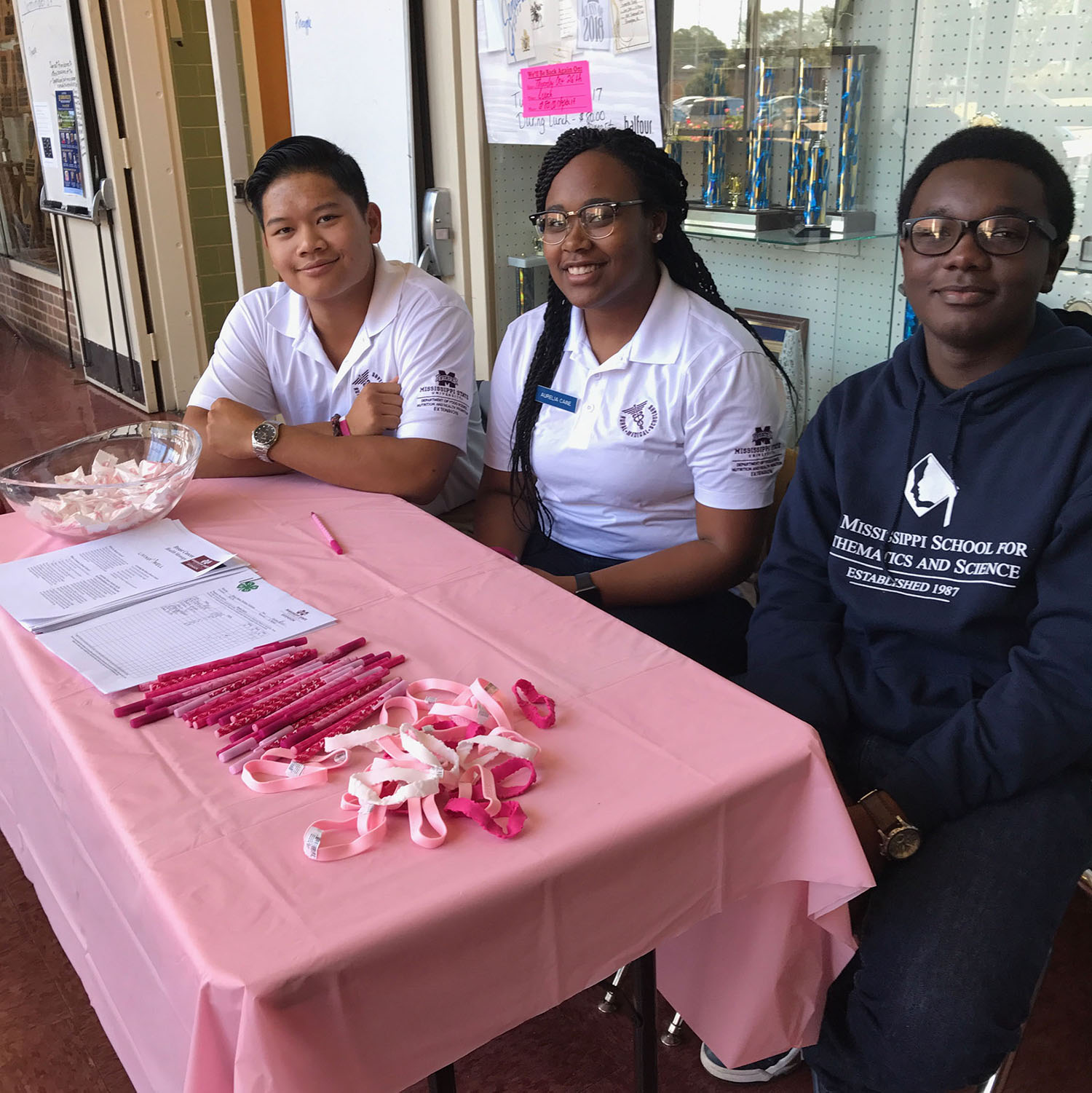 Daniel, Aurelia, and Carey are manning a Breast Cancer Awareness Booth
