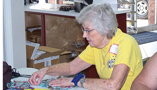 A clothing volunteer is pinning fabric.