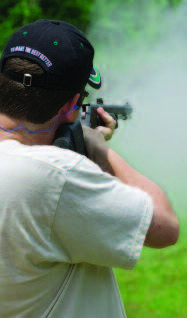 A man firing a muzzleloader as smoke fills the air.